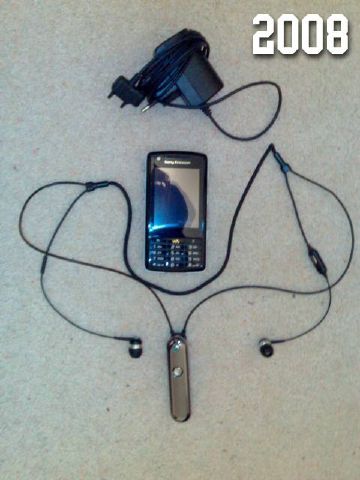 Photo of a Sony Ericsson W960i smartphone, a Bluetooth headset and a single charger