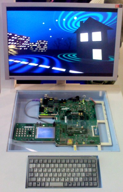 Photo of the FreeWay tech demo setup. A monitor at the top is playing a promotional video. Below is a development board (behind a sheet of glass) that is running the demo, and a keyboard