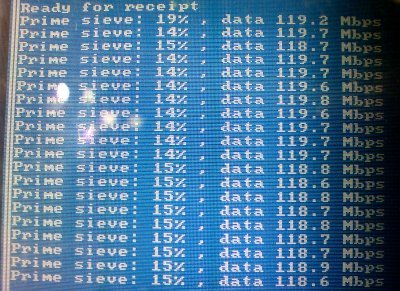 Close-up of the screen on the development board. It's displaying log messages that are reporting the data throughput. The values are all between 118 and 120Mpbs.