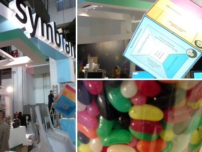 Photo collage of the "Symbian" sign above the stand, a lit-up rotating cube on the stand and a close-up of some jellybeans
